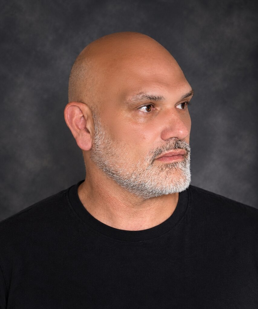 Side profile portrait of electronic music producer Philippe JOUMARD for the website contact page, against a dark textured background.
